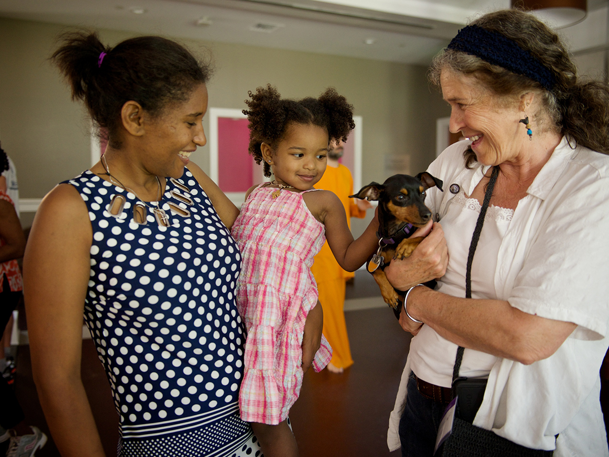 A woman holding a small child next to another woman holding a dog