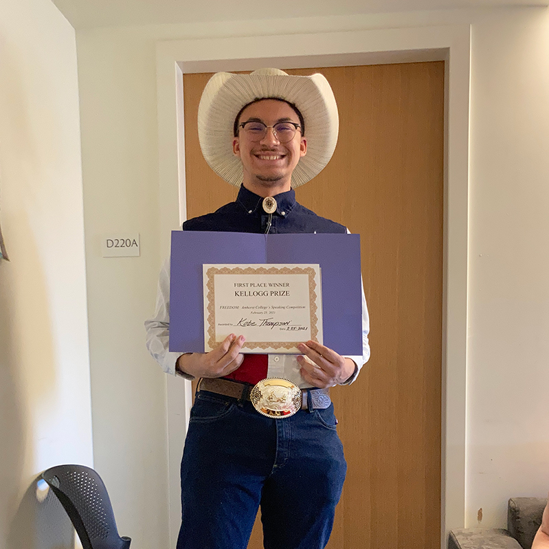 A young man in a cowboy hot holding a certificate