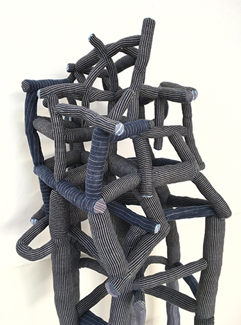 A piece of abstract art sculpture made up of gray twisting tubes