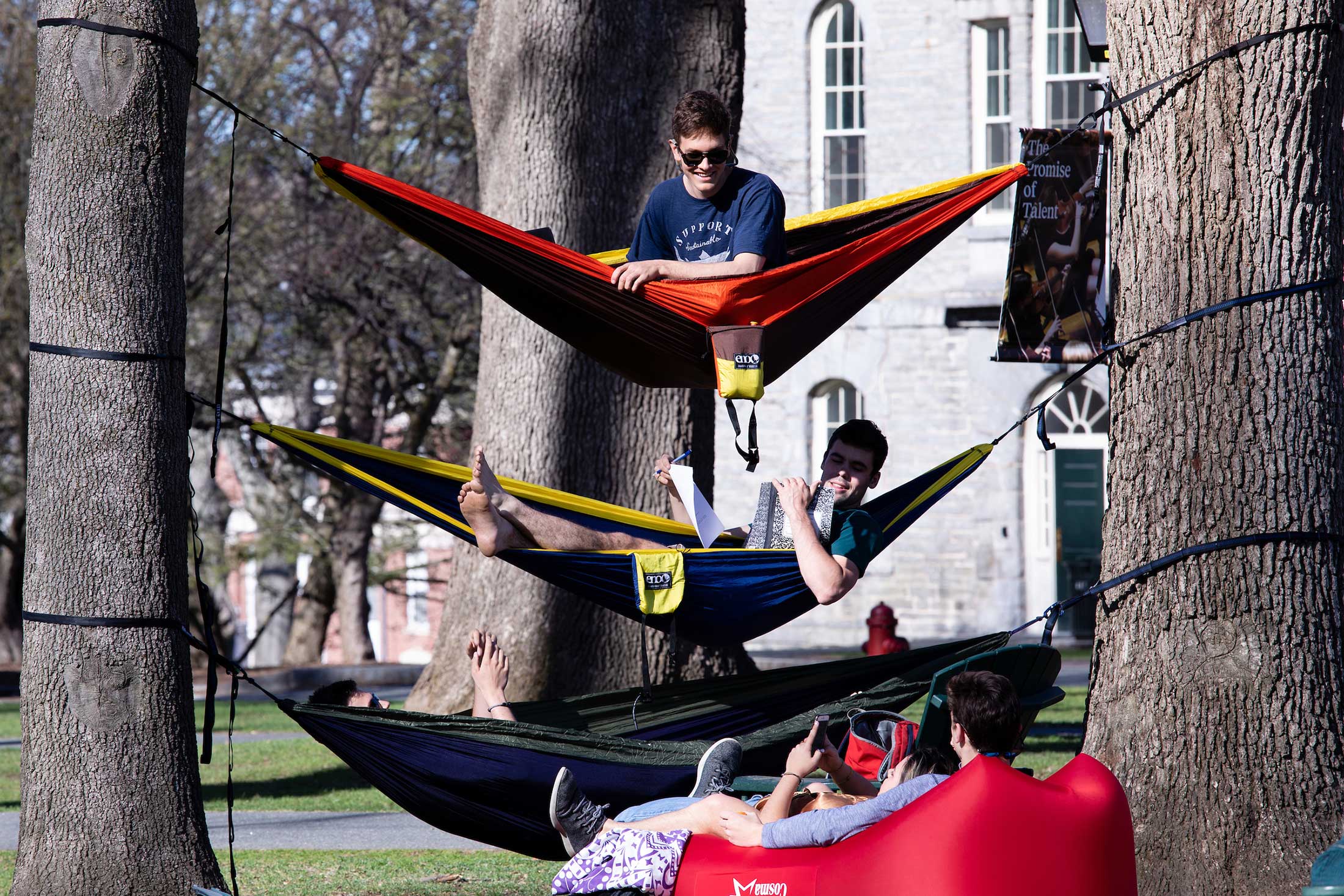 Three students relax in hammocks on the Amherst College campus