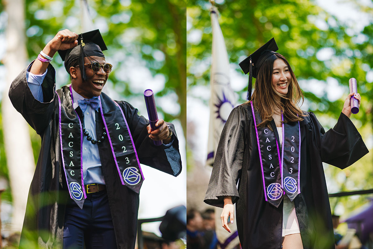 Two graduates celebrate receiving their diplomas.