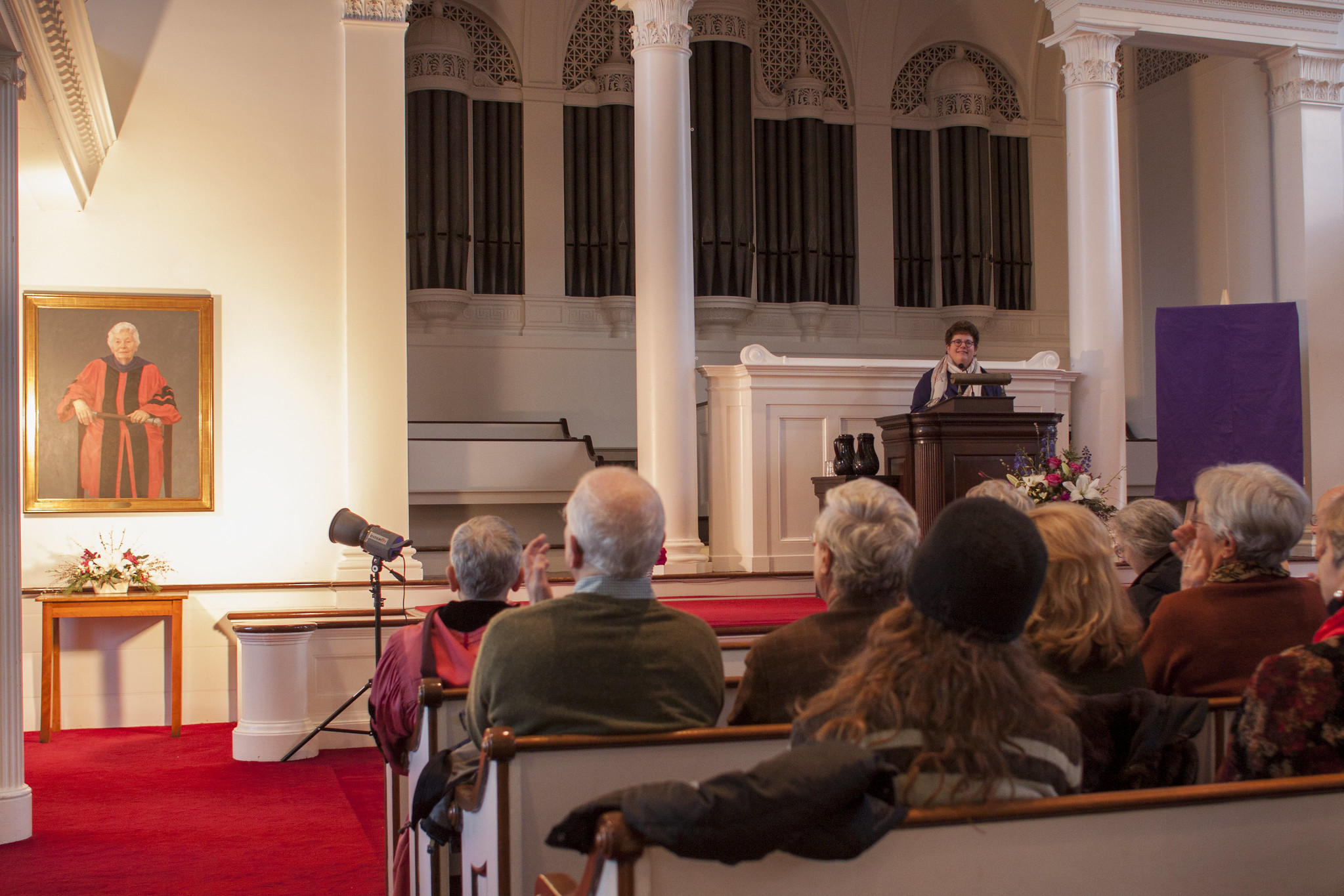 Biddy Martin speaks in Johnson Chapel with Rose Olver portrait on the wall