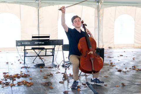 Oren Tirschwell gives flourish at the end of a cello performance in outdoor tent