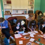 students assemble postcards while wearing masks
