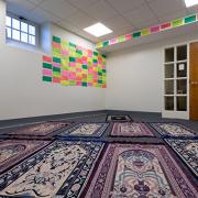A room with bright colored notes on the wall and prayer rugs on the floor